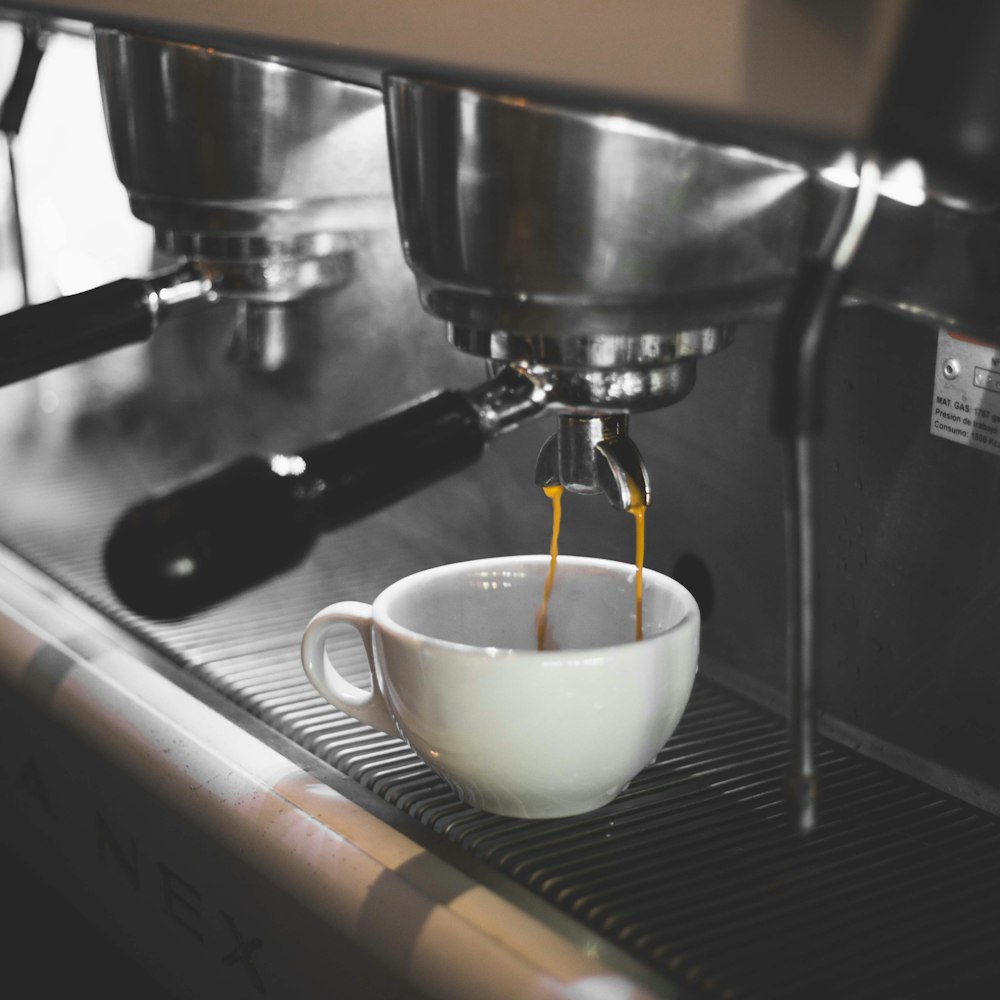 white ceramic teacup on black espresso machine