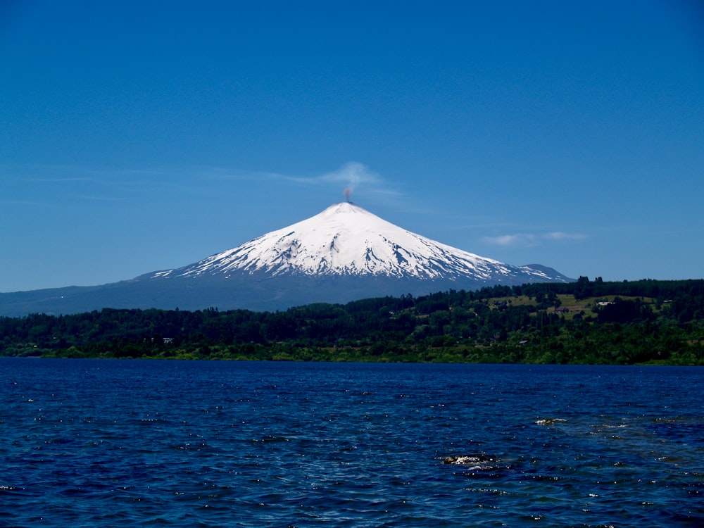 green and white mountain near body of water under blue sky during daytime