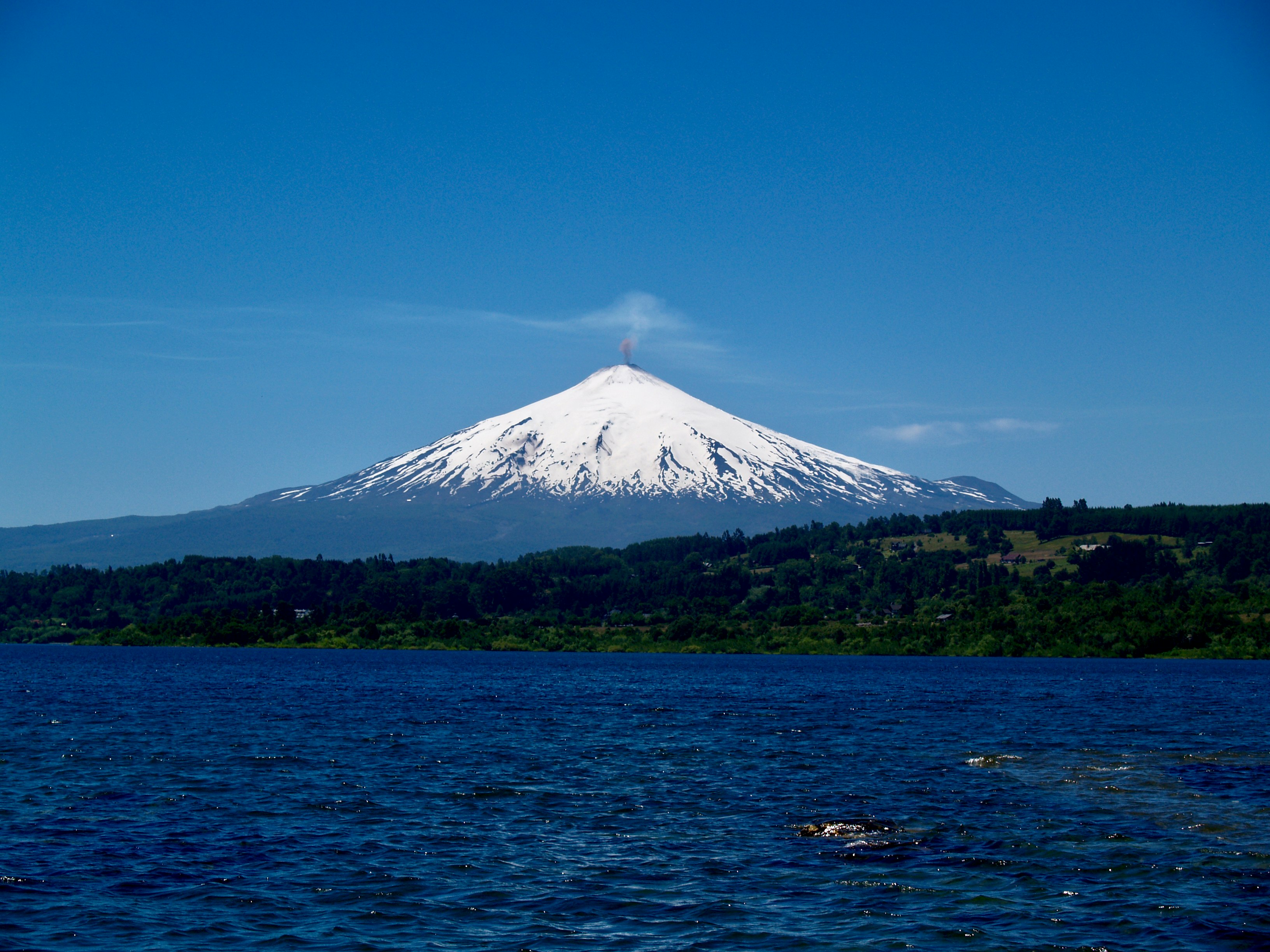 green and white mountain near body of water under blue sky during daytime