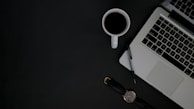 An office worker’s desk with a sleek watch, notebook, and a cup of coffee.