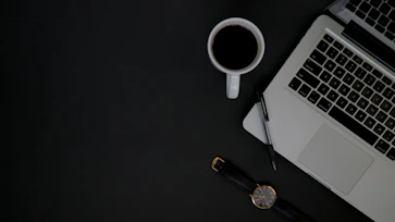 A professional office desk with a laptop, notebook, and a cup of coffee, symbolizing communication.