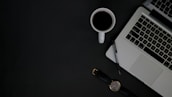 An open laptop on a desk with a notepad and coffee cup, symbolizing a productive work environment.