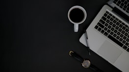 An open laptop on a desk with a notepad and coffee cup, symbolizing a productive work environment.