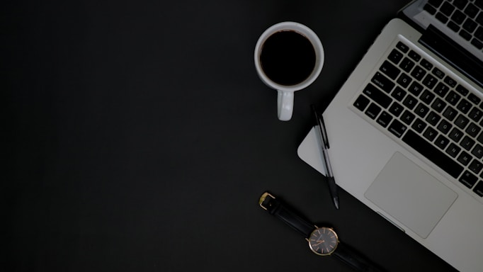 A professional office desk with a laptop, notebook, and a cup of coffee.