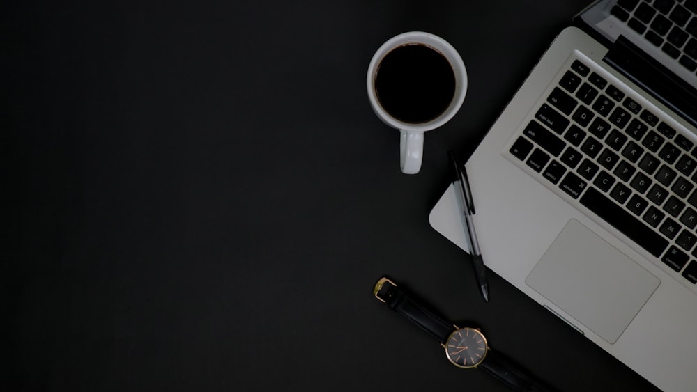 white ceramic mug beside silver round analog watch