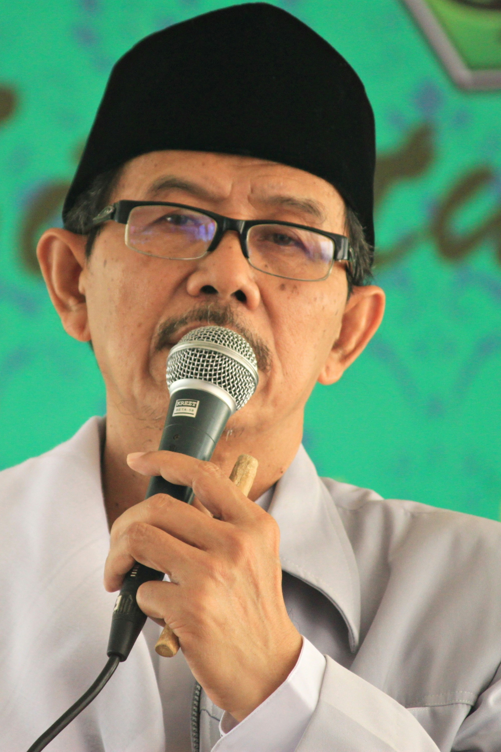 pria berbaju putih memegang mikrofon