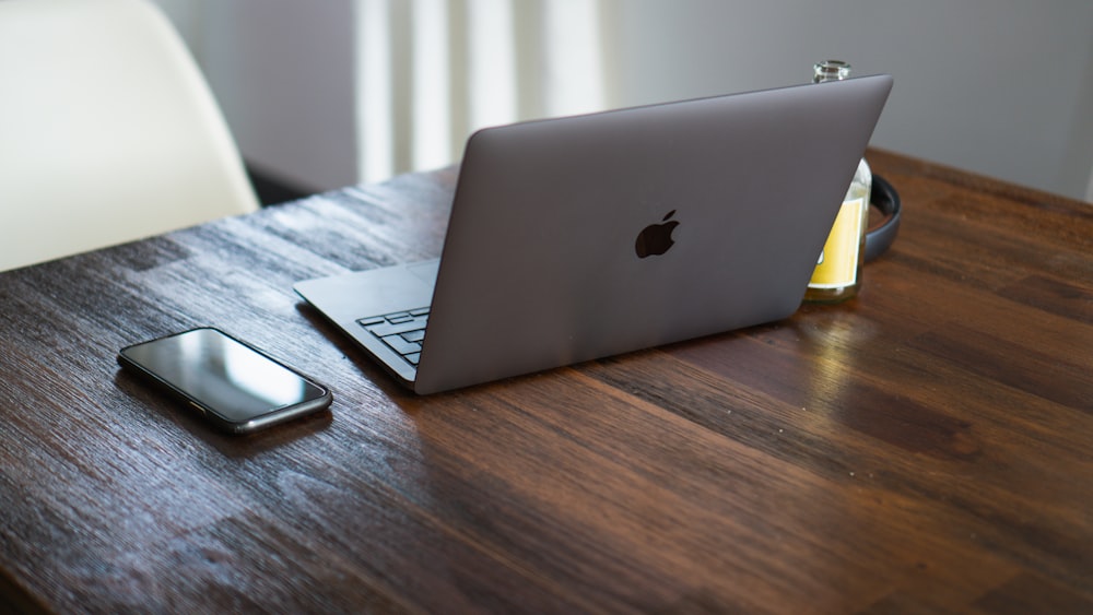 silver macbook on brown wooden table