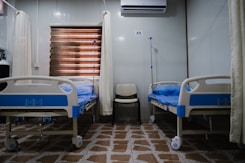 white split type air conditioner over white and blue hospital bed