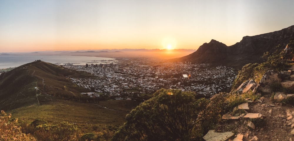 city skyline during sunset with green trees and mountains