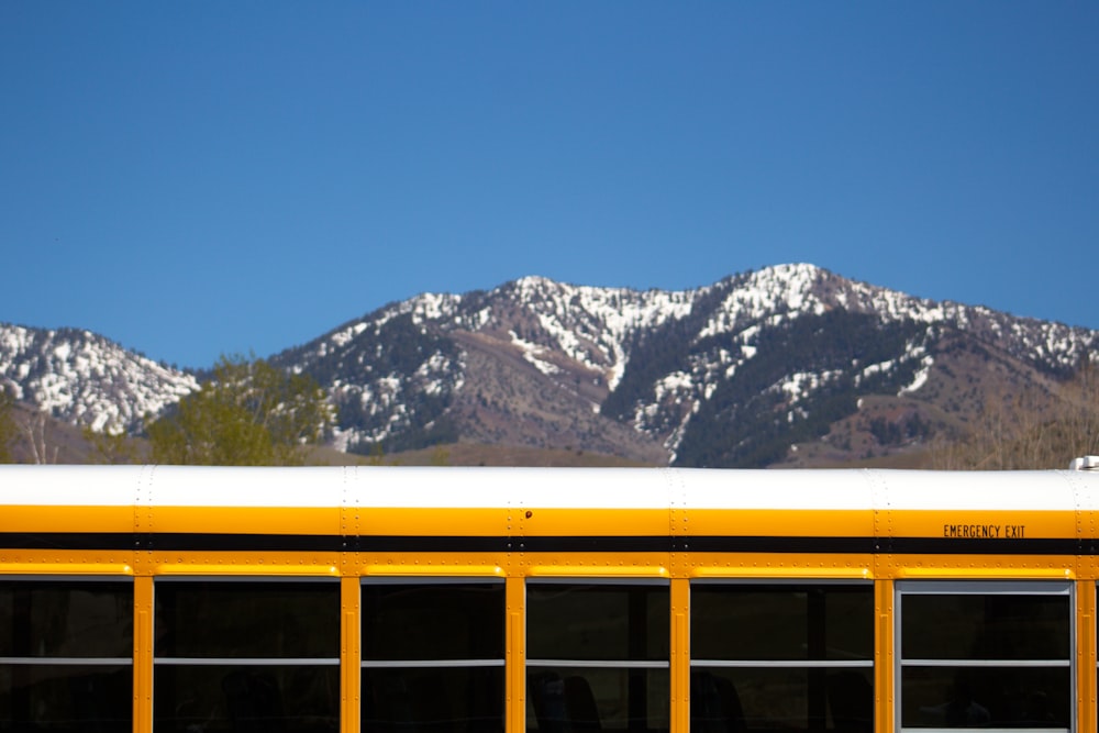 yellow school bus on road near snow covered mountain during daytime