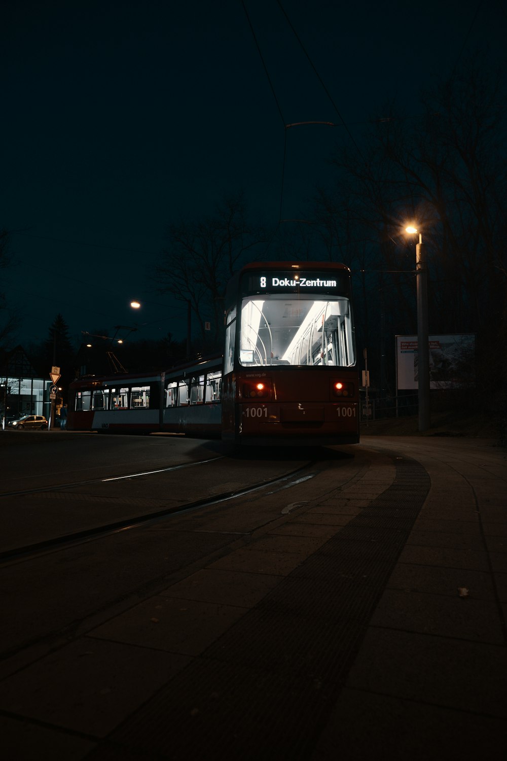 red and white tram on road during night time