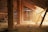 An old, rustic attic with wooden beams and walls, filled with scattered debris and straw on the floor. Light filters in through gaps in the wall slats, casting shadows and highlighting the textures of the wooden surfaces.