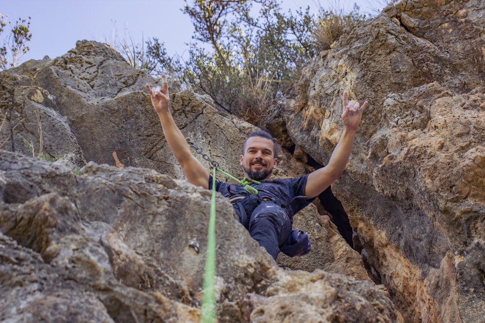 man in blue t-shirt climbing on rock during daytime