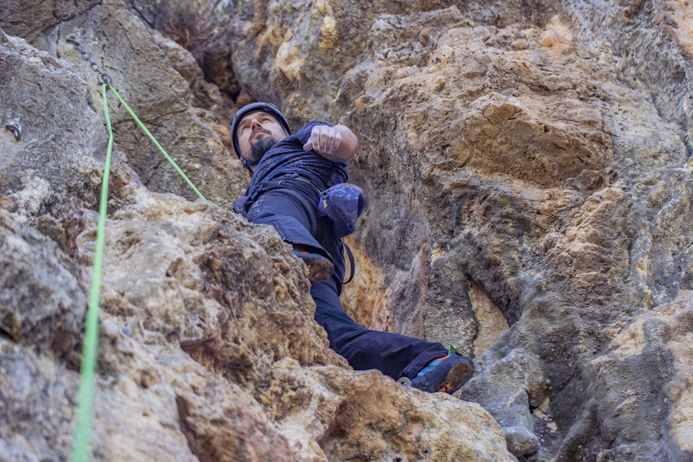 person in blue jacket climbing on brown rock mountain during daytime