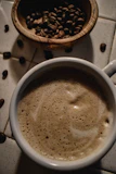 Artistic shot of a steaming cup of black coffee with coffee beans scattered around
