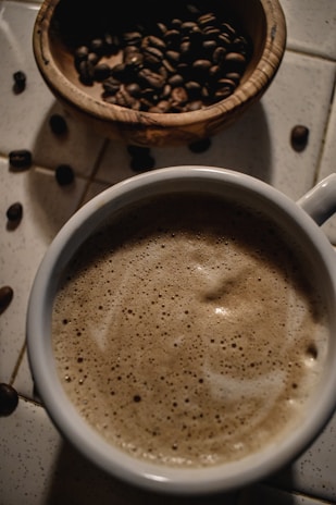 Close-up of a steaming cup of coffee next to a plate with butter and cheese slices.