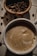 Close-up of a steaming cup of cappuccino on a wooden table with coffee beans scattered around.