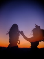 Smiling faces sharing music and dance around a fire as twilight settles in the Andes.