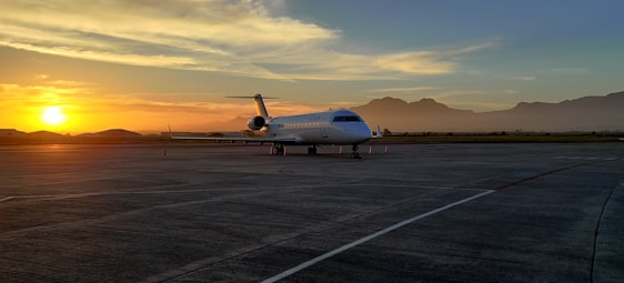 A sleek private jet parked on a quiet tarmac at dusk, bathed in soft golden light.