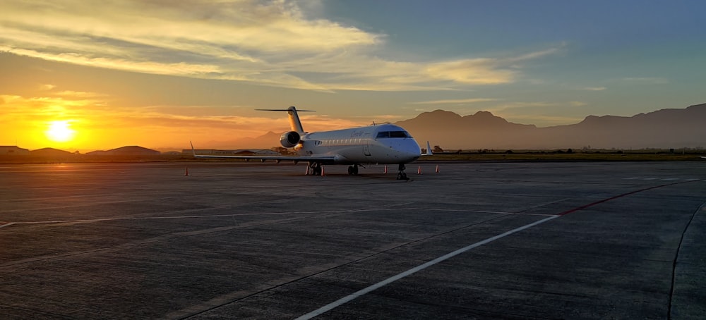 Weißes Flugzeug am Flughafen bei Sonnenuntergang