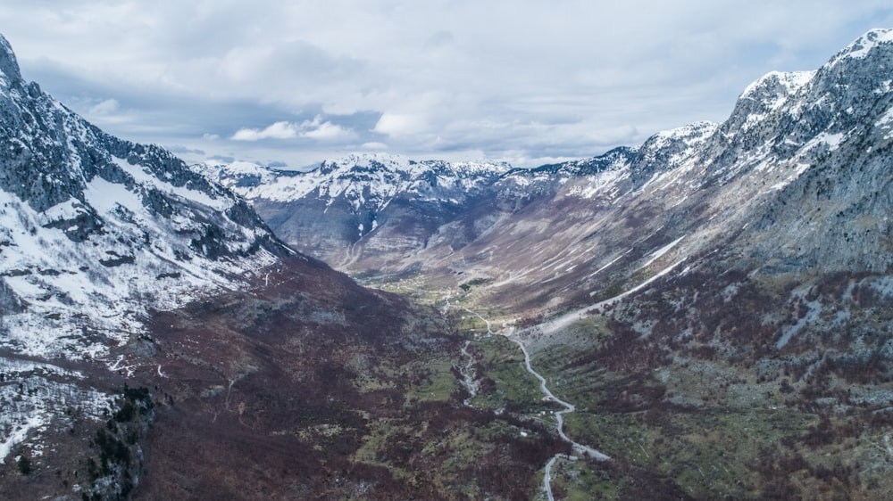 montagnes vertes et brunes sous des nuages blancs et un ciel bleu pendant la journée