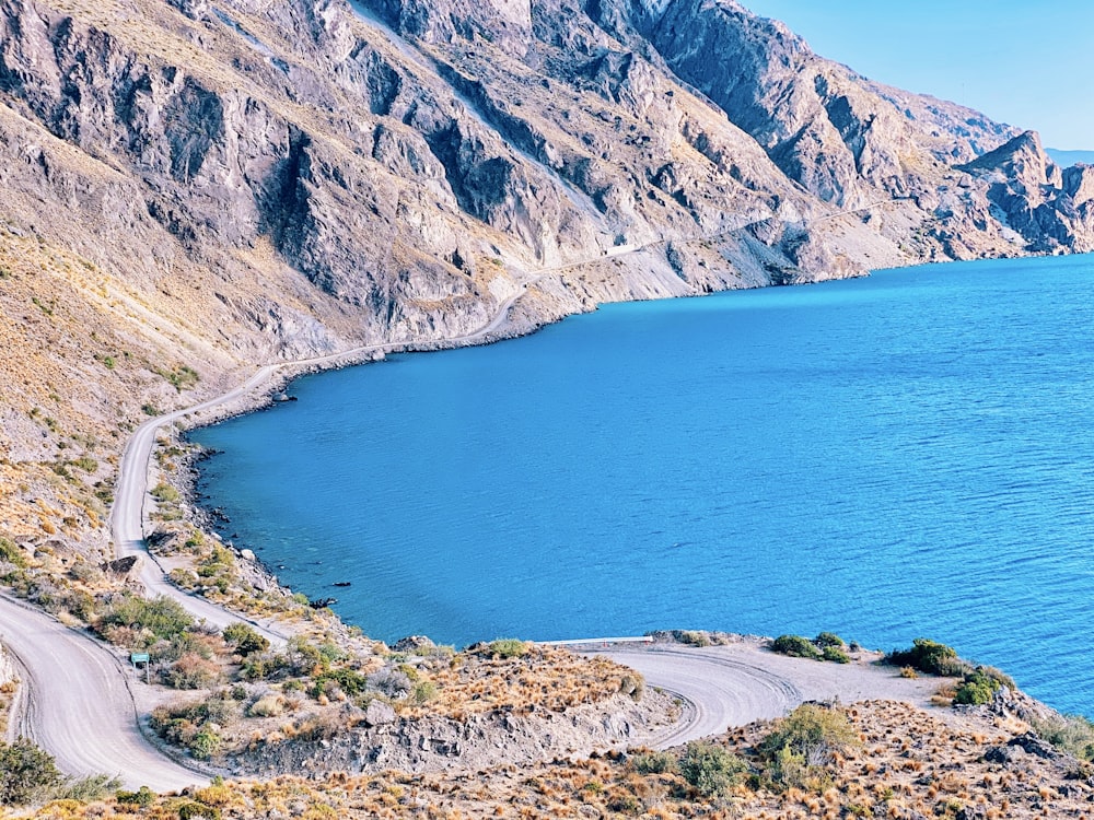 blue sea beside brown and green mountains during daytime