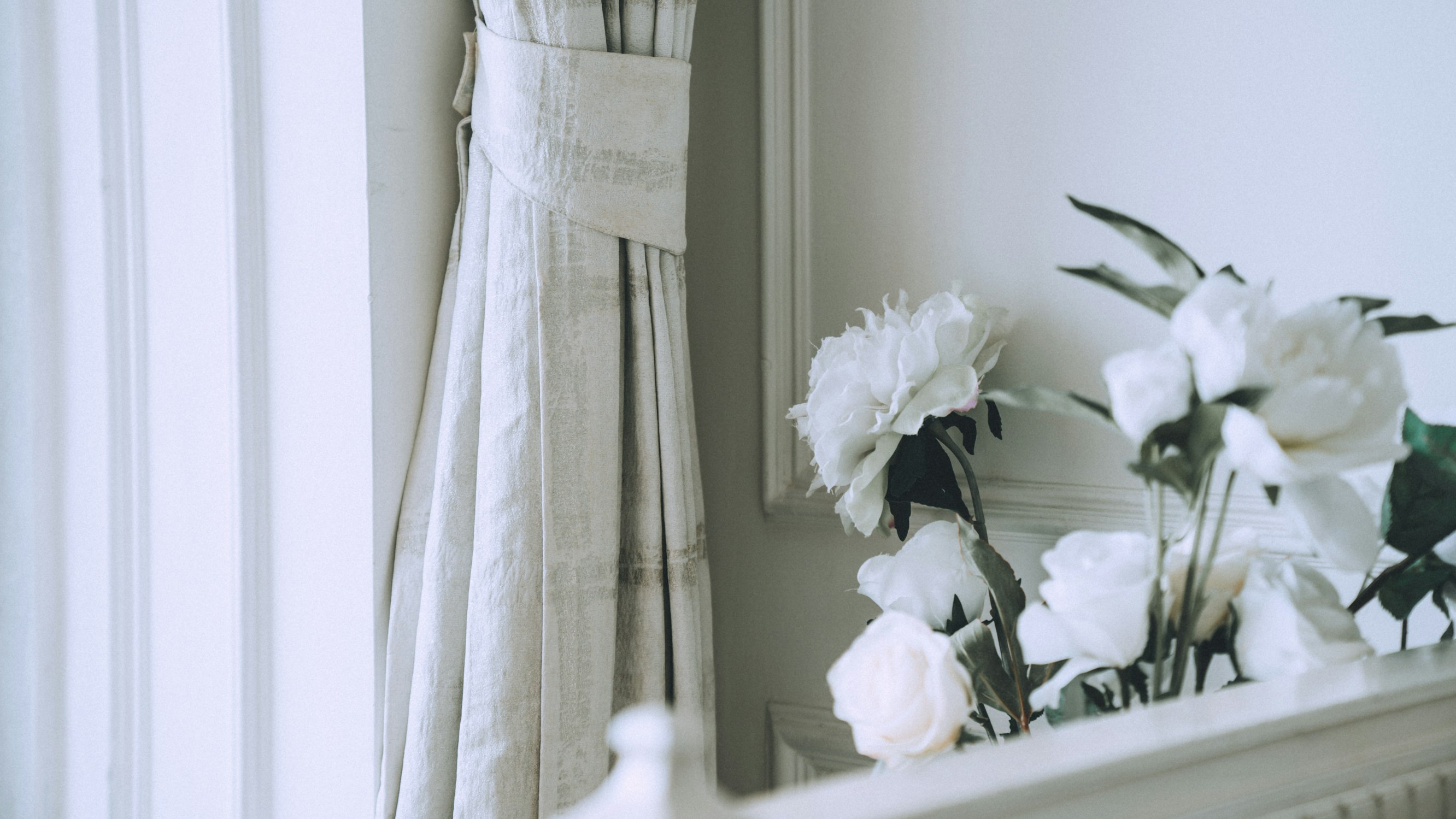 White blackout curtains by window and flowers - Photo by Arun Sharma on Unsplash