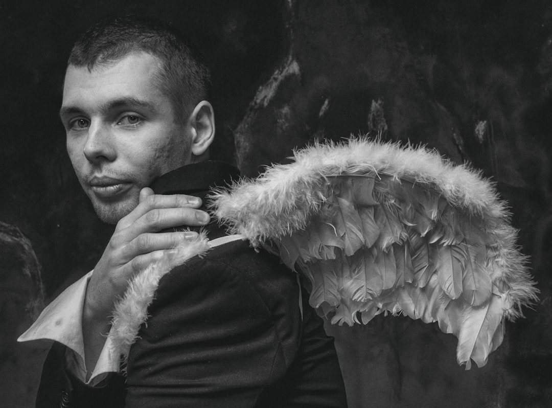 man in black long sleeve shirt holding white feather