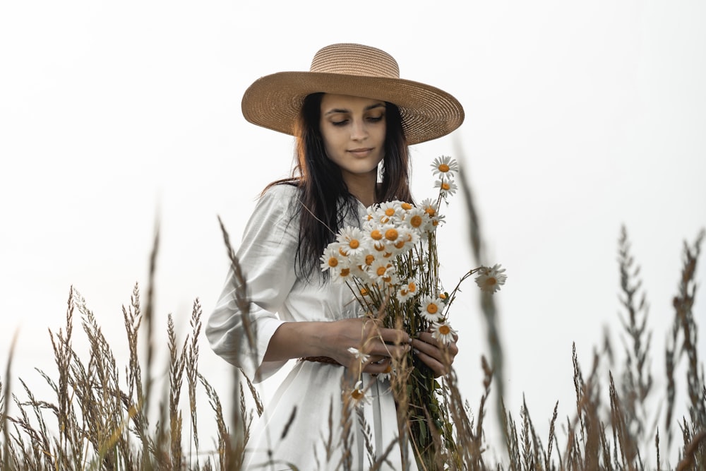 woman in white long sleeve shirt holding white flowers