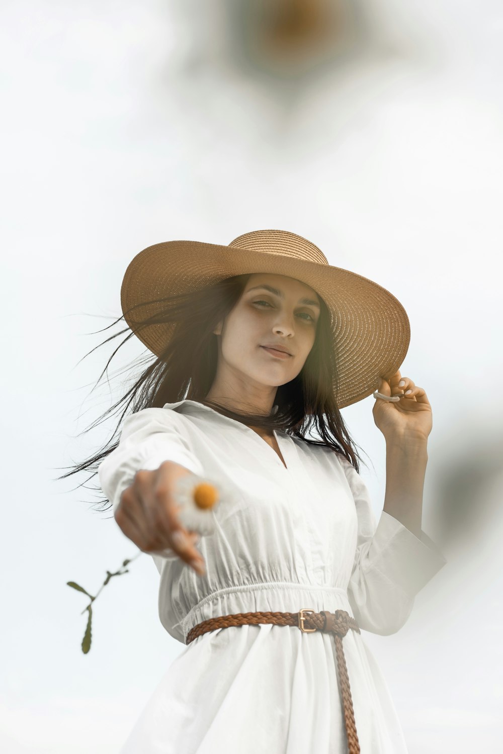 woman in white long sleeve shirt wearing brown straw hat holding orange fruit