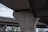 A close-up view of large concrete pillars supporting an elevated highway or bridge structure. The scene captures the geometric patterns and the texture of raw concrete. Sparse trees can be seen in the background, adding a touch of greenery to the predominantly industrial setting.