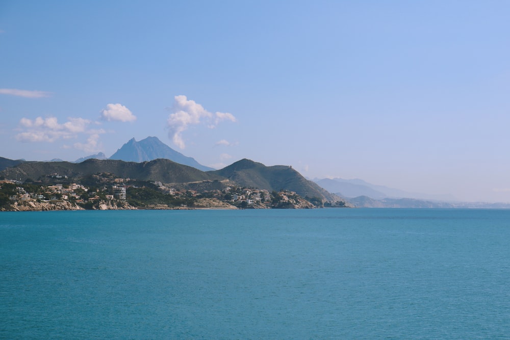 blue sea near mountain under blue sky during daytime