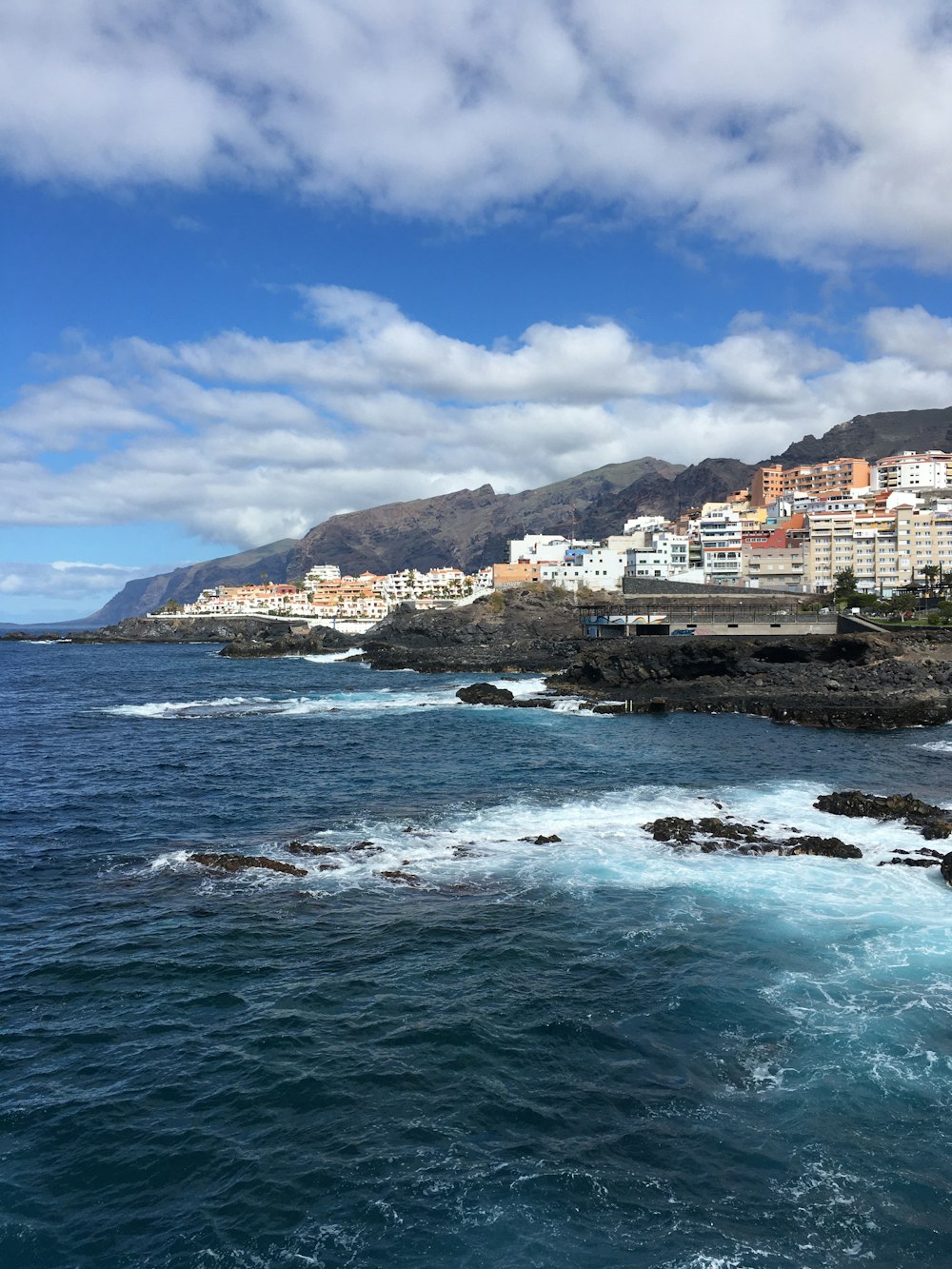 white and brown concrete buildings near body of water under blue sky during daytime