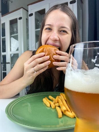 Happy customer enjoying a delicious burger and a cold drink at a modern restaurant table.