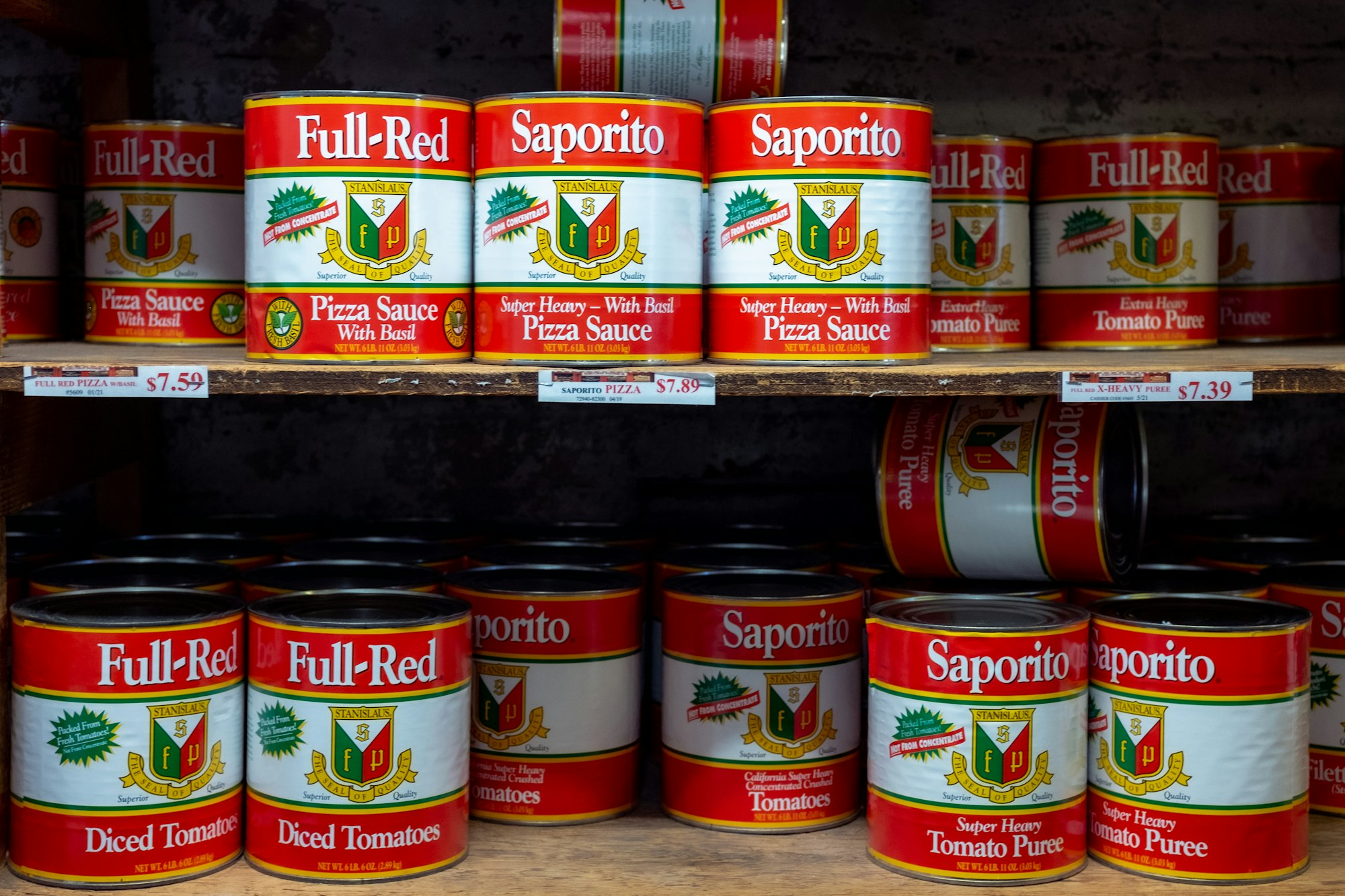 A store shelf with a variety of tomato-based cans, including tomato purée and pizza sauce