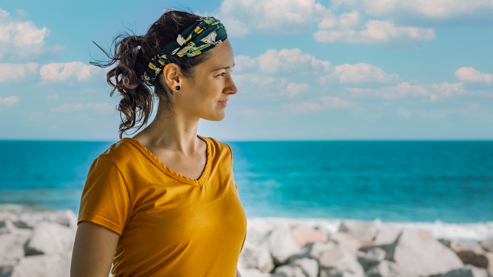 Femme en chemise jaune à col rond portant un bandeau floral vert et bleu