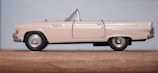 Side view of a blue classic convertible scale model on a wooden surface.