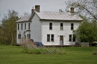 white and gray wooden house on green grass field during daytime