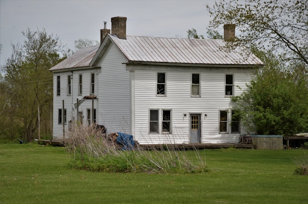 white and gray wooden house on green grass field during daytime