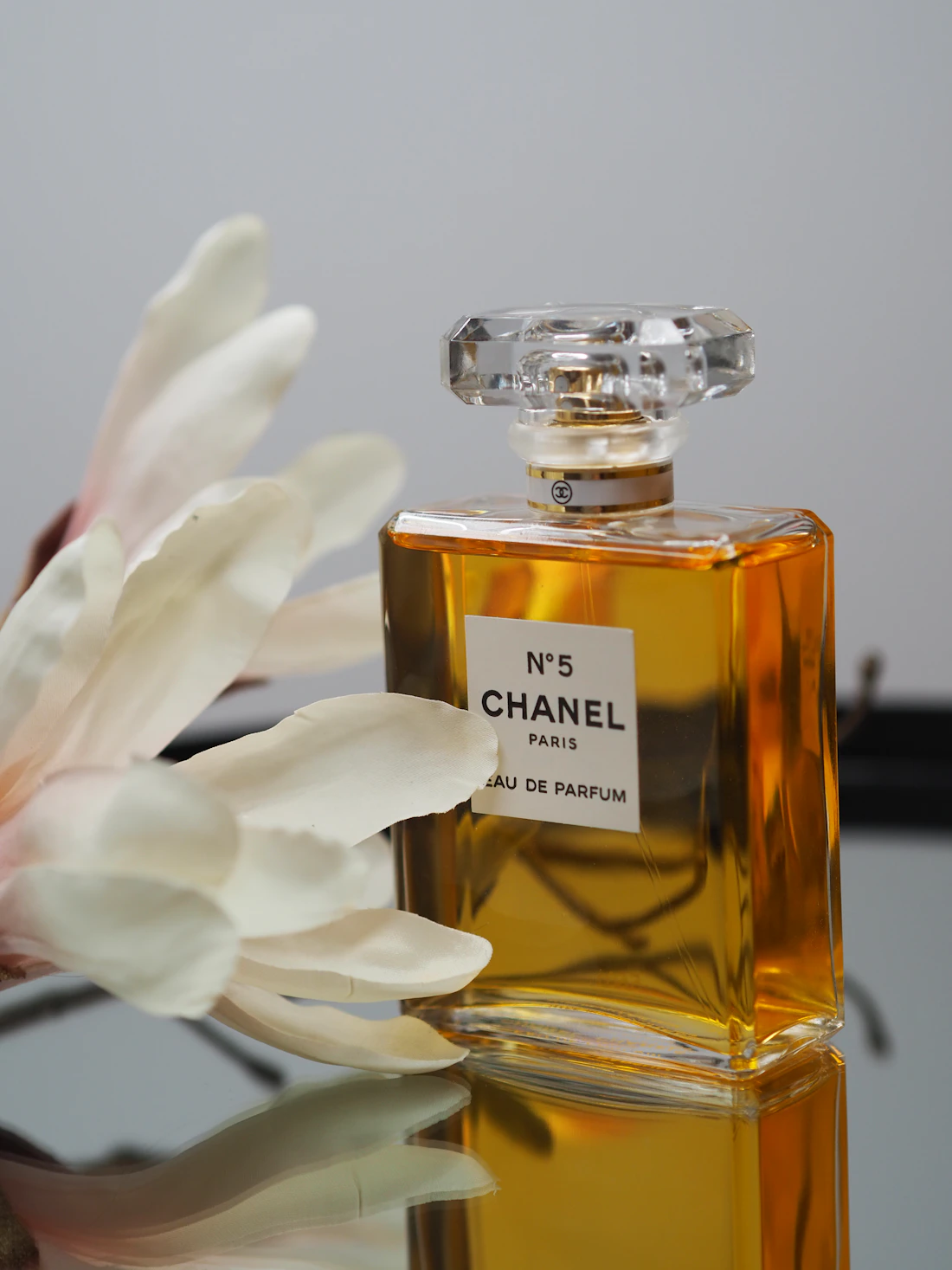 Frasco de perfume ao lado de uma flor branca