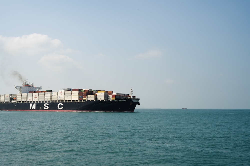 black cargo ship on sea under white sky during daytime