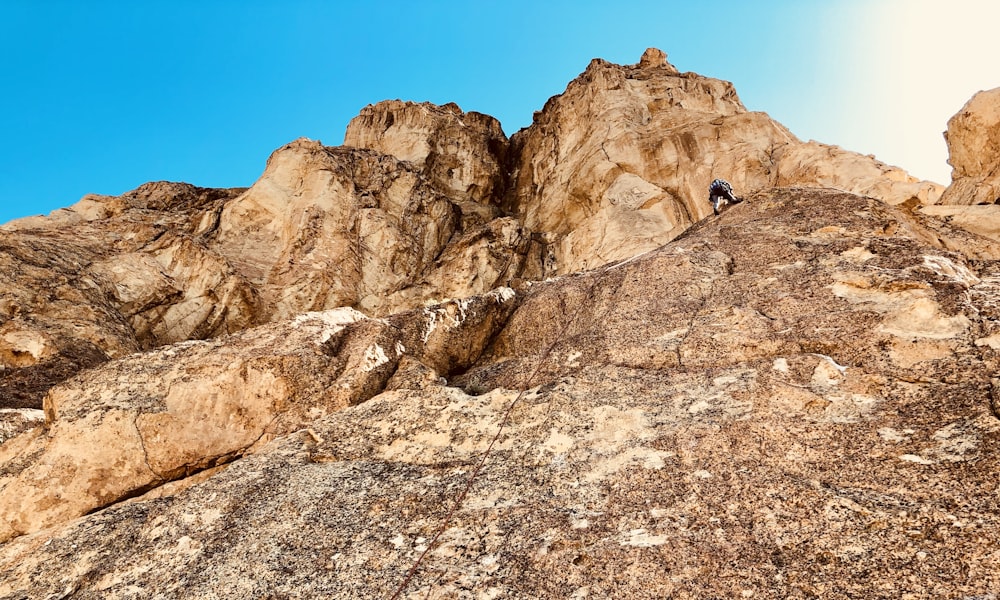 person climbing on rocky mountain during daytime