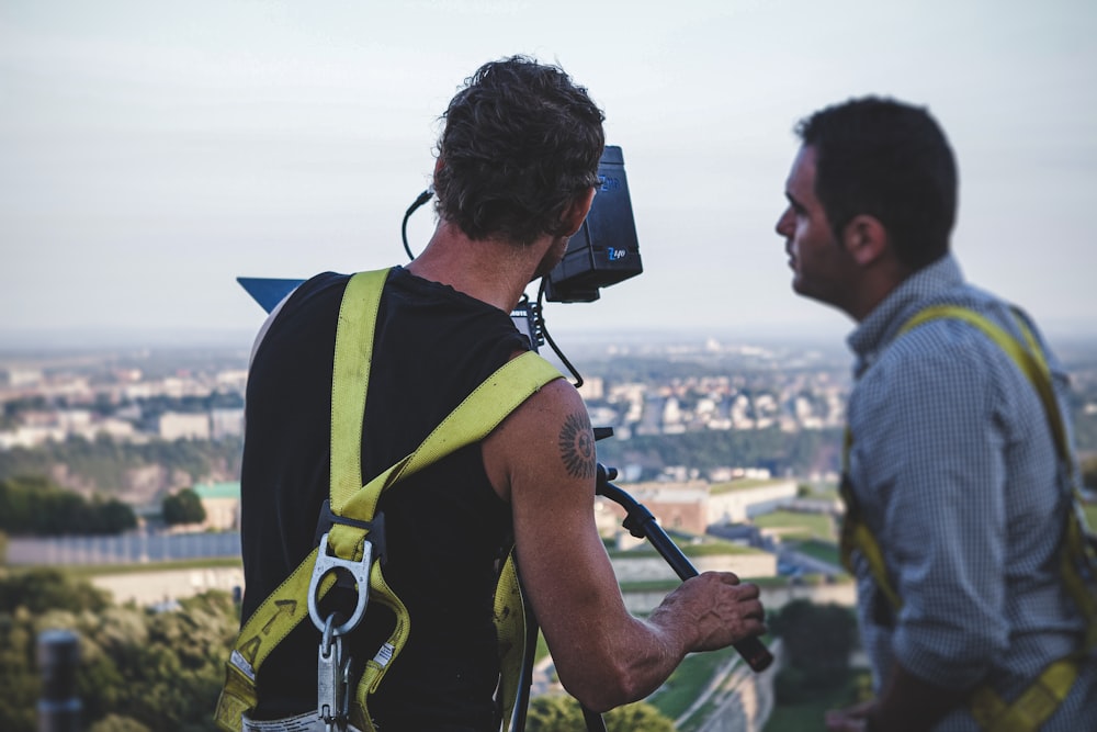 man in green and black backpack holding black camera