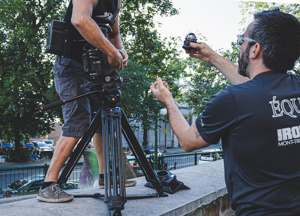 man in black t-shirt and black shorts holding black dslr camera