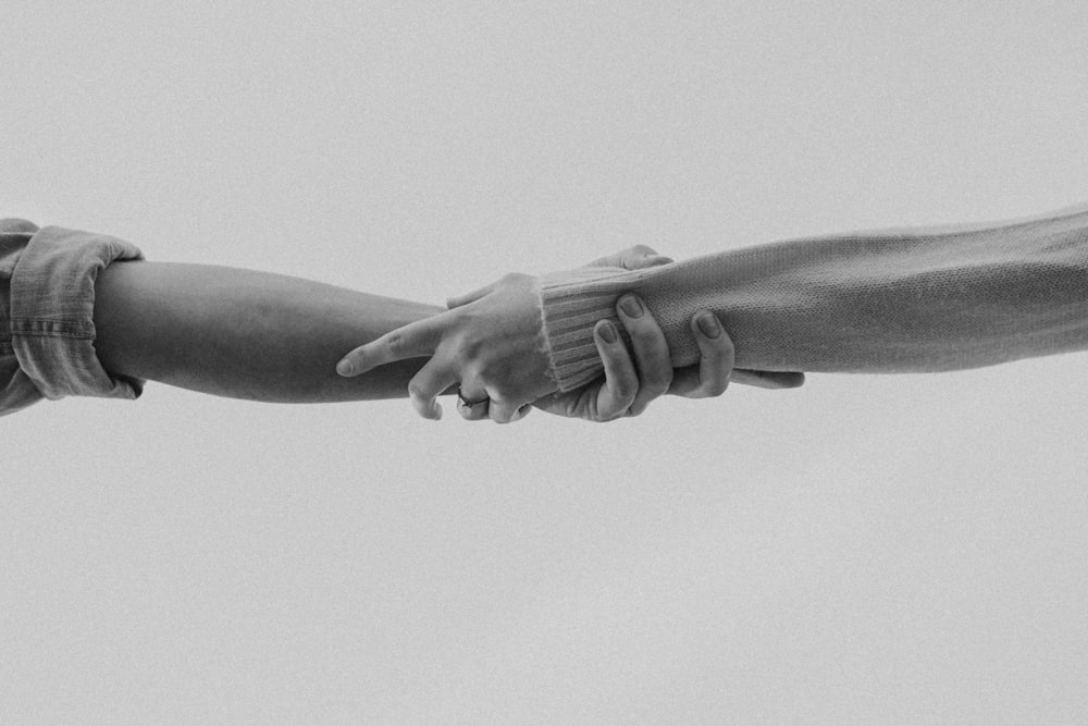 Foto en escala de grises de una persona tomada de la mano