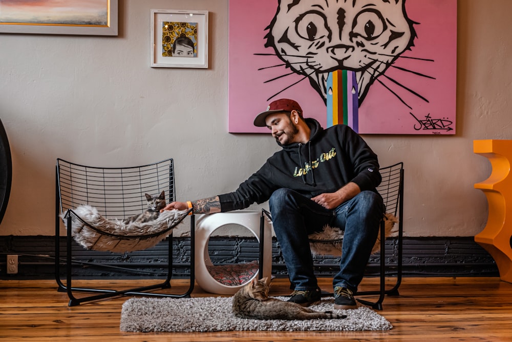 man in black sweater and blue denim jeans sitting on white wicker armchair