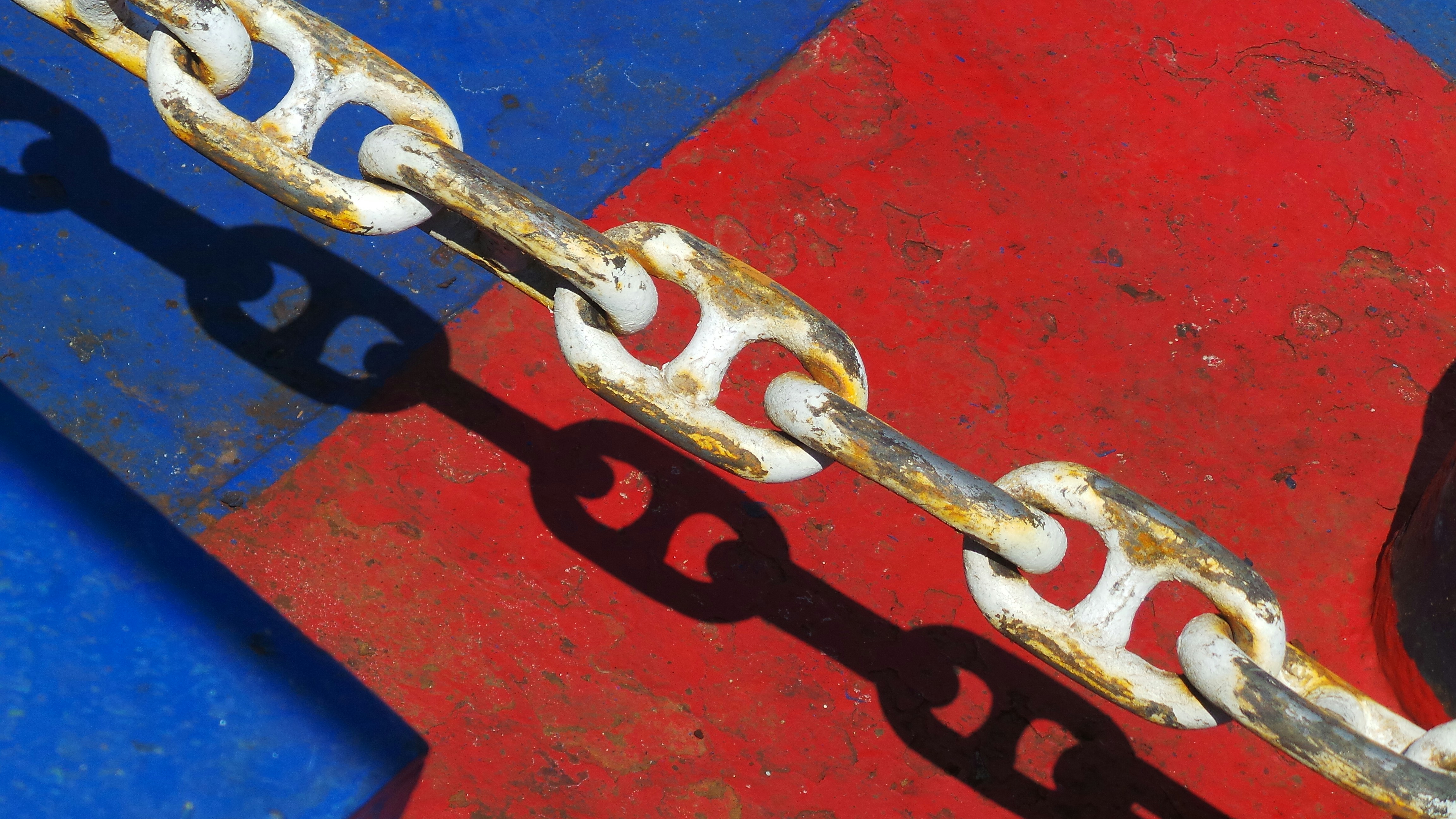 black metal chain on red concrete wall