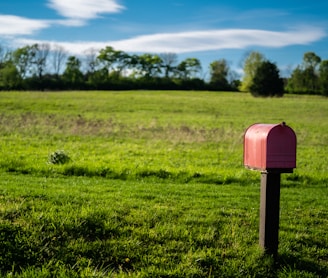 red mail box on green grass field during daytime