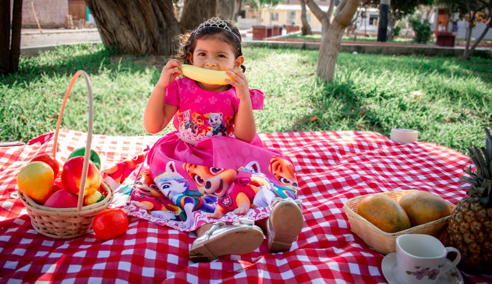 girl in pink and white floral dress eating bread