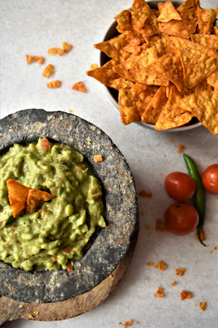 Colorful bowls of guacamole and salsa roja with handmade tortilla chips